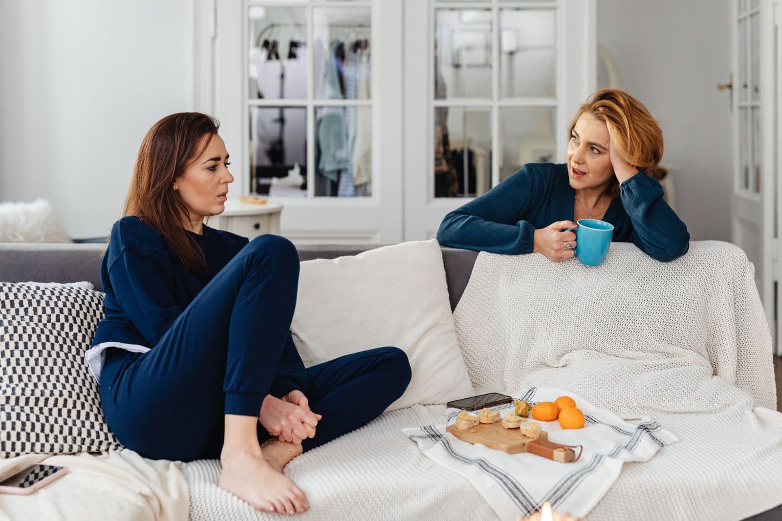 Two women having a calm, supportive conversation together on a couch